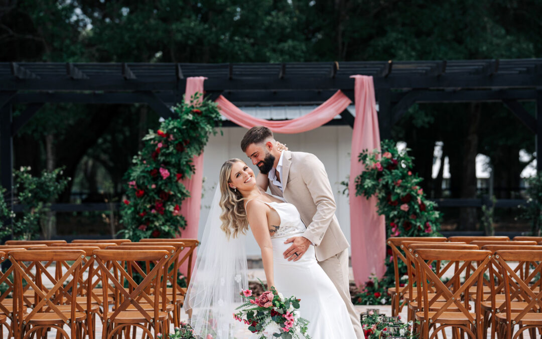 Outdoor wedding ceremony setup with floral arch and newlywed couple smiling