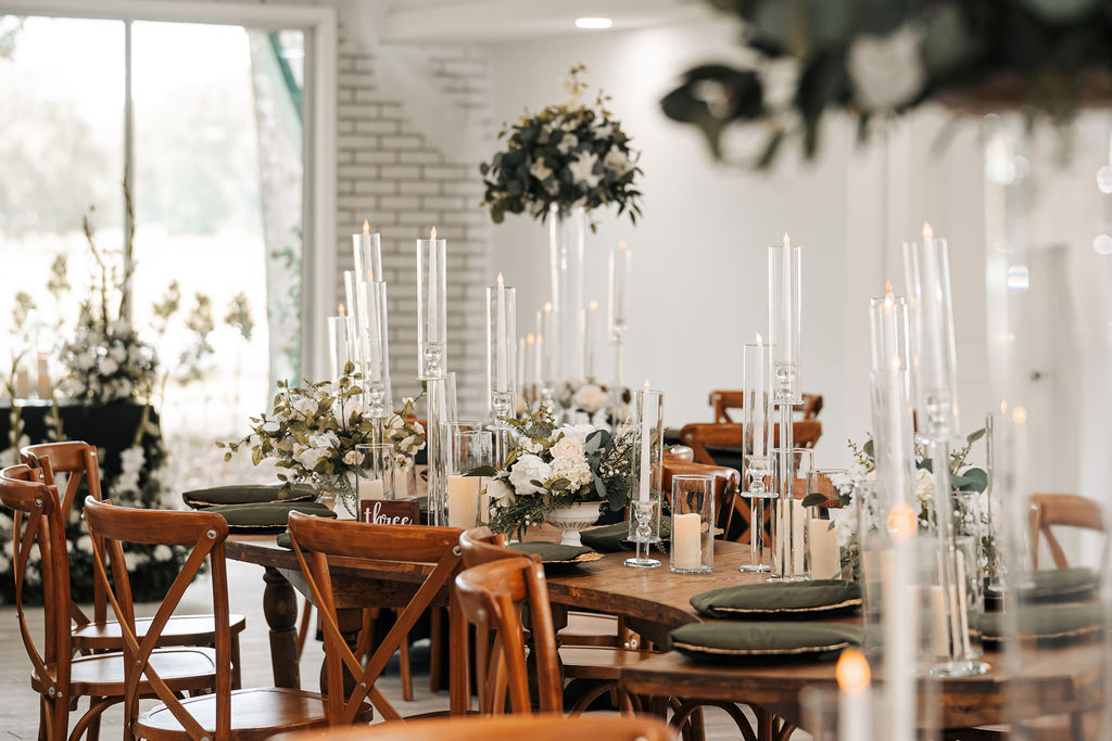 Intimate and elegant table setting at a wedding reception with natural wood and a moody floral and candlelight aesthetic.